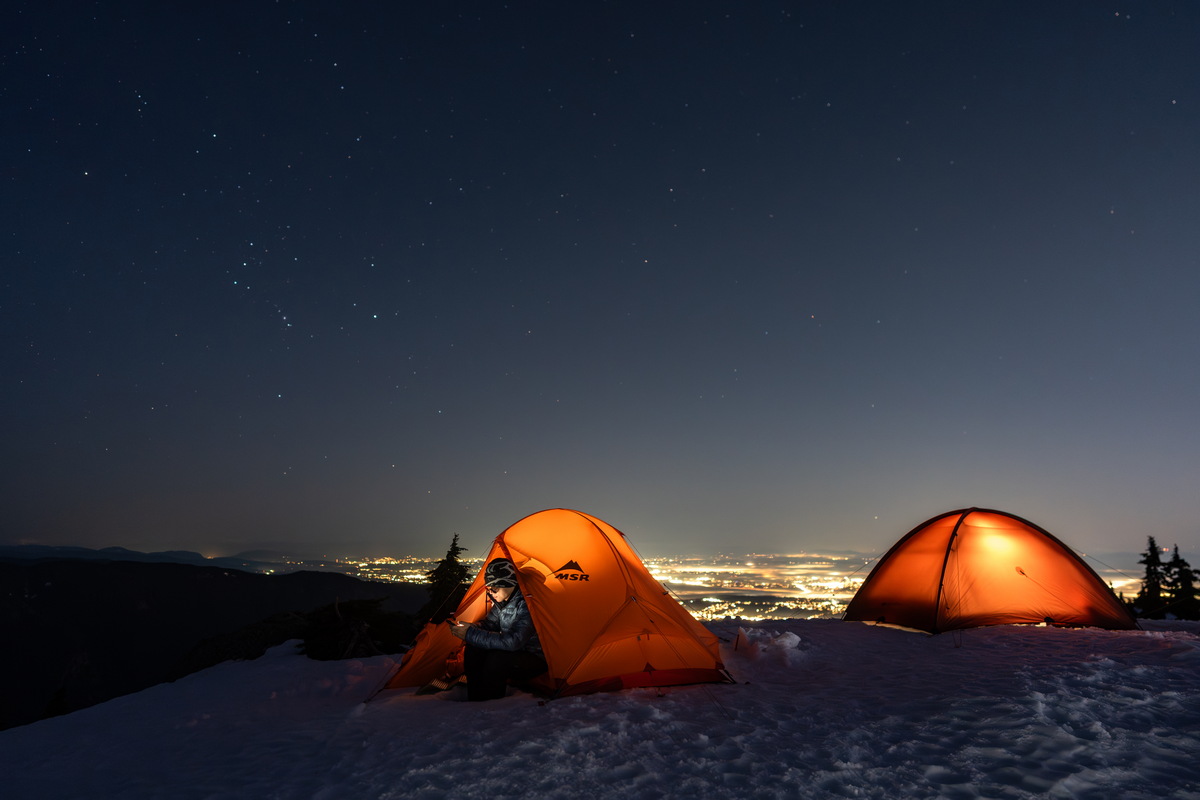 雪地帐篷夜景,Lit tents under the night sky, Mount Seymour;24mm f/2,两顶亮灯的帐篷、山下的城市灯火与星空。