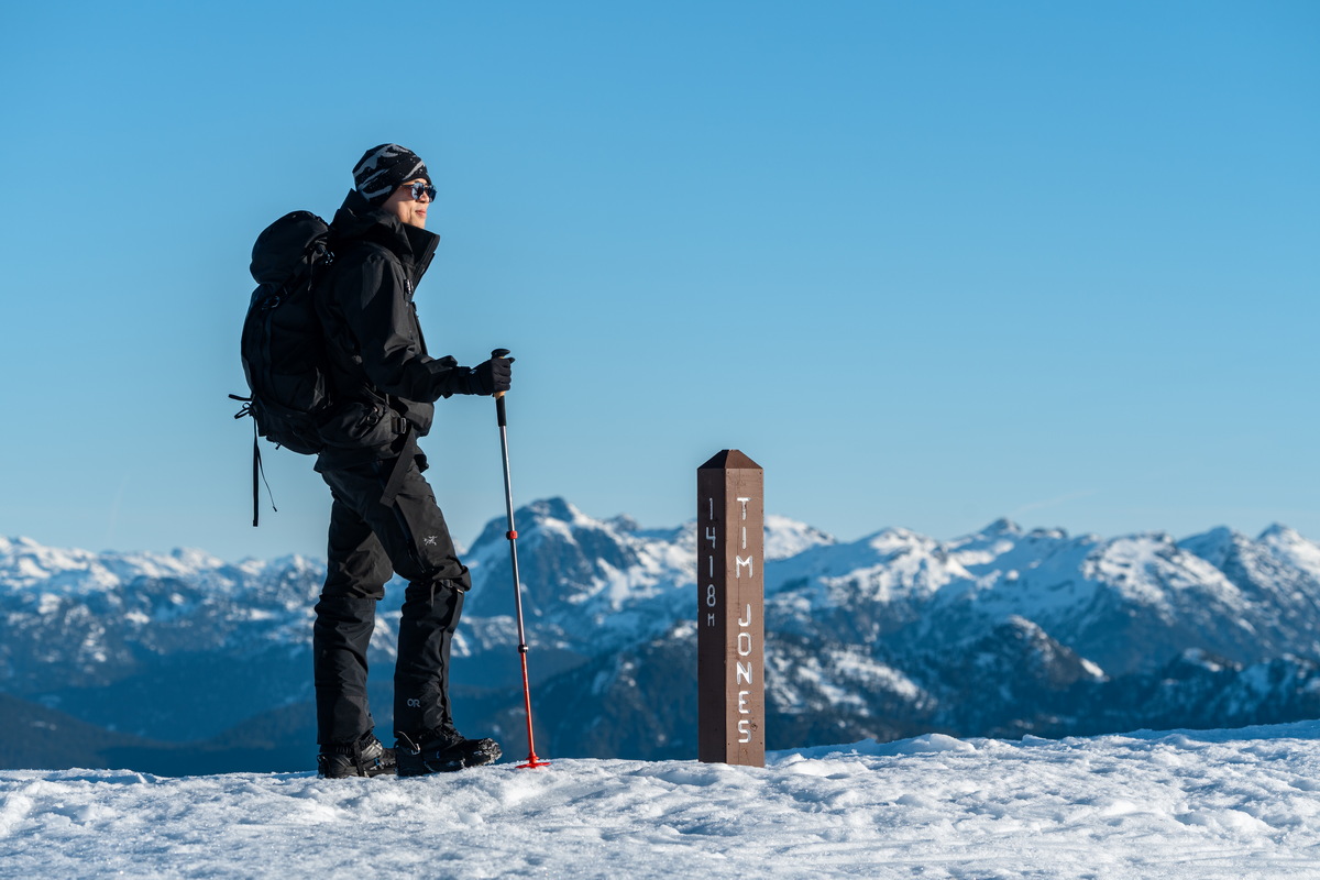 下山途中的步道标记,Hiker at a trail marker, Mount Seymour;10:59,晴天下山,背景是积雪的北岸群峰。